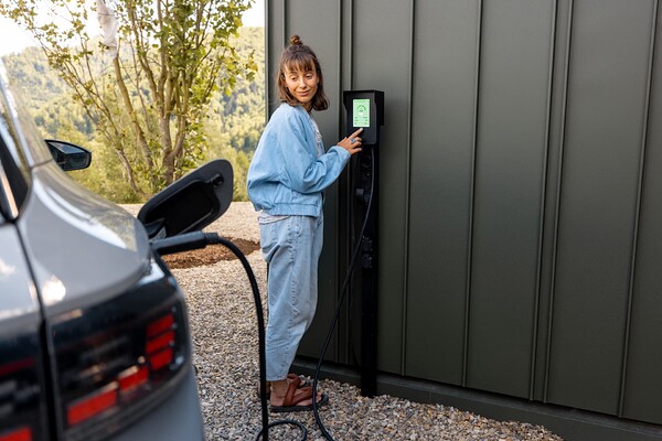 Femme utilisant sa borne de recharge pour recharger son véhicule électrique